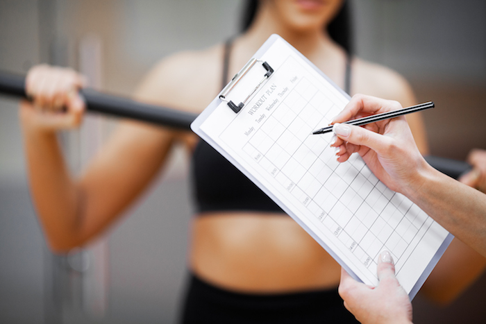 fitnessplan-sporttrainer-belaeuft-sich-auf-trainingsplan-nahaufnahme