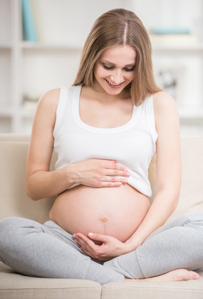 Mama schwanger auf Sofa und schauf auf ihren Bauch.jpg