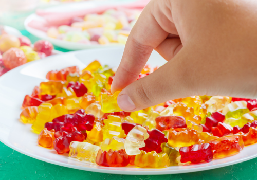 Hand nimmt Gummibärchen vom Teller (500 x 350 px).png