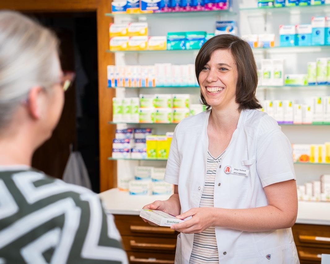 Apothekerin übergibt ein Medikament an eine Kundin