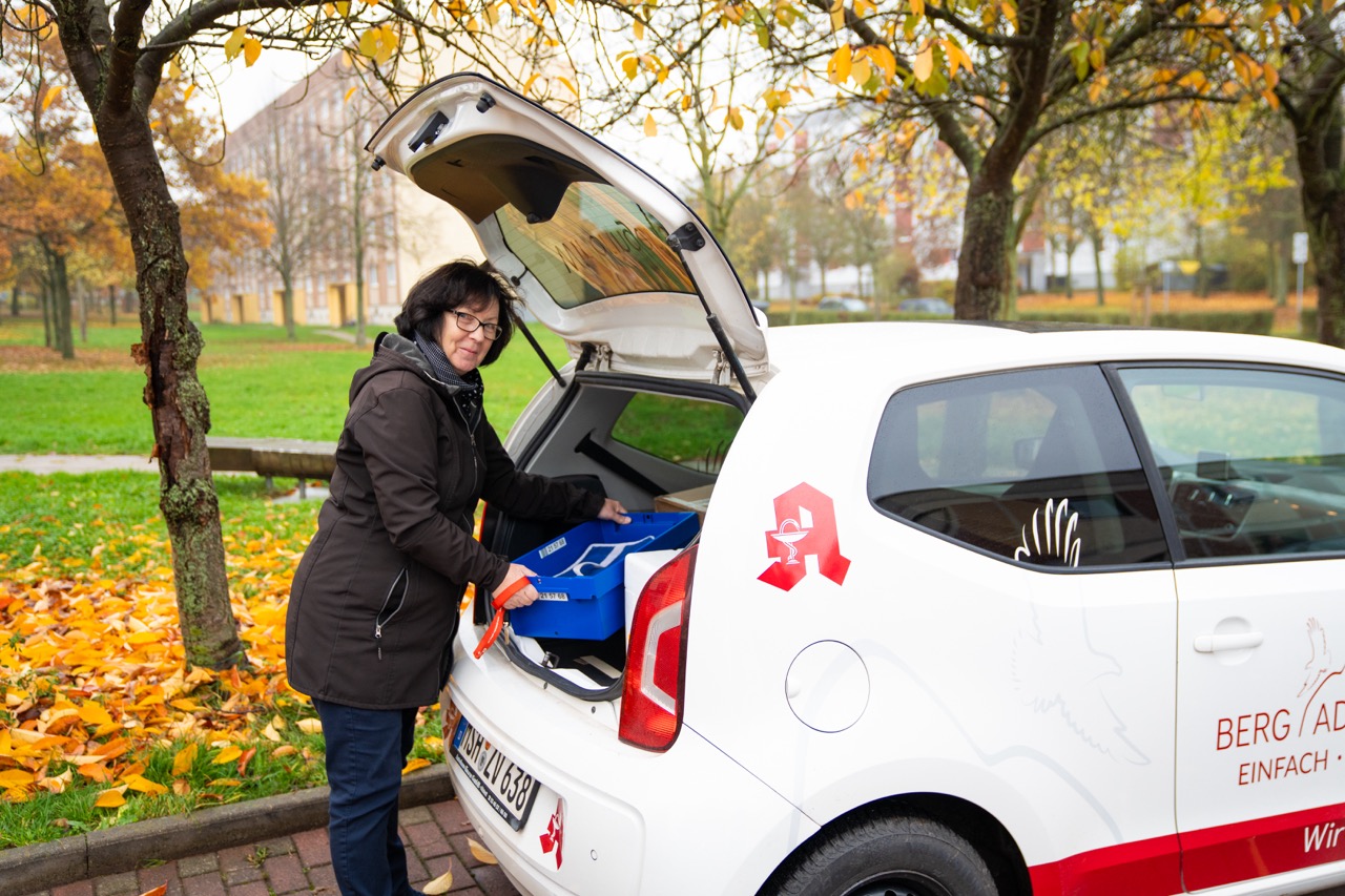 Mitarbeiterin am Kofferraum des Apotheken-Lieferfahrzeuges