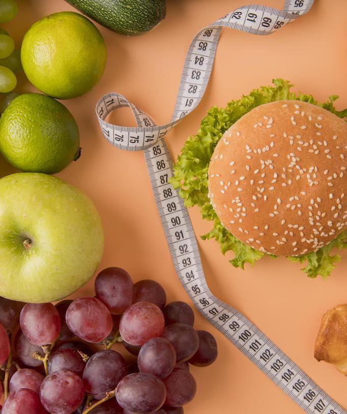 gesundes essen und ungesundes essen fürchte und hamburger auf dem tisch durch maßband getrennt