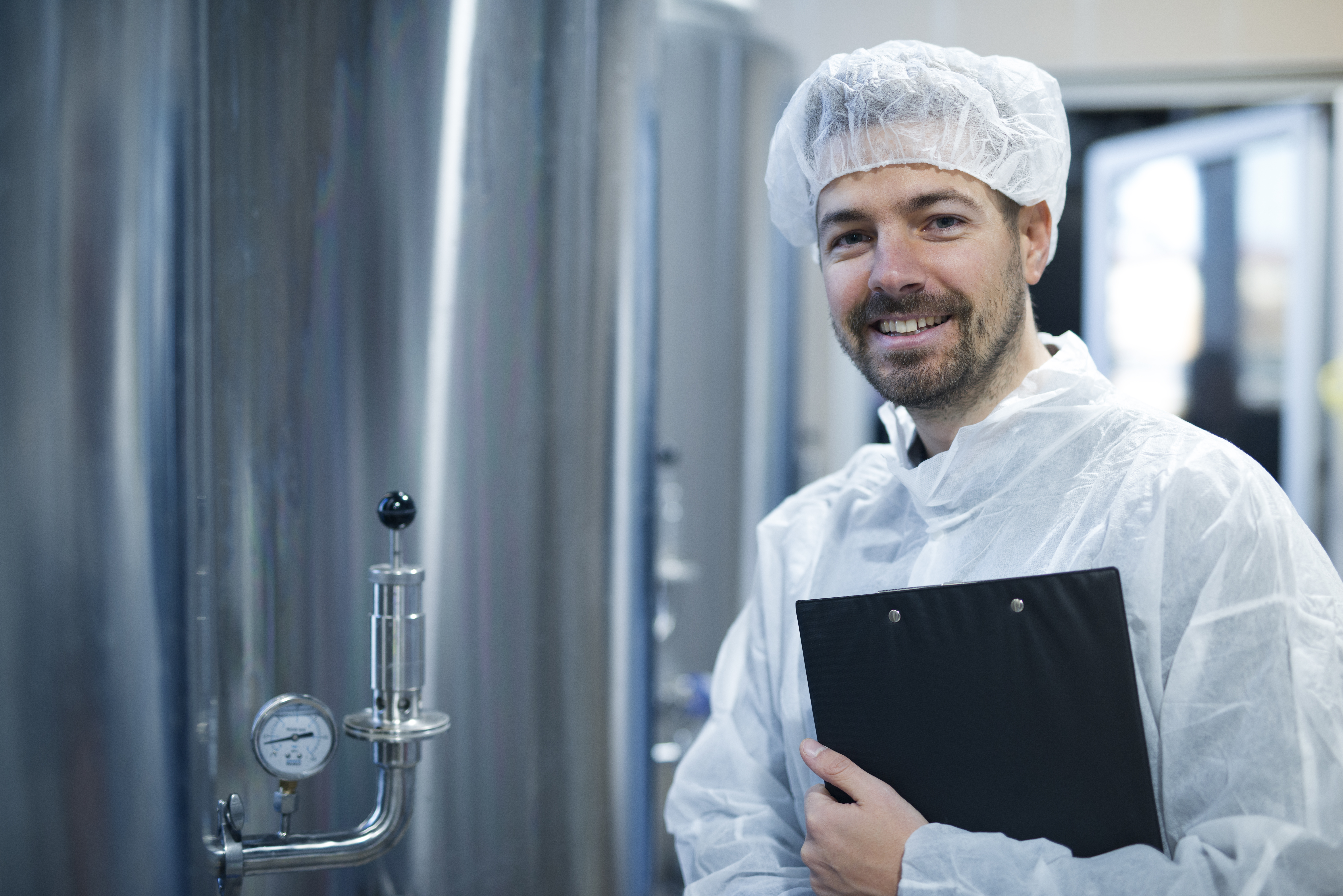 technologist-white-protective-uniform-hairnet-standing-by-chrome-reservoirs-with-pressure-gauge-food-processing-plant.jpg
