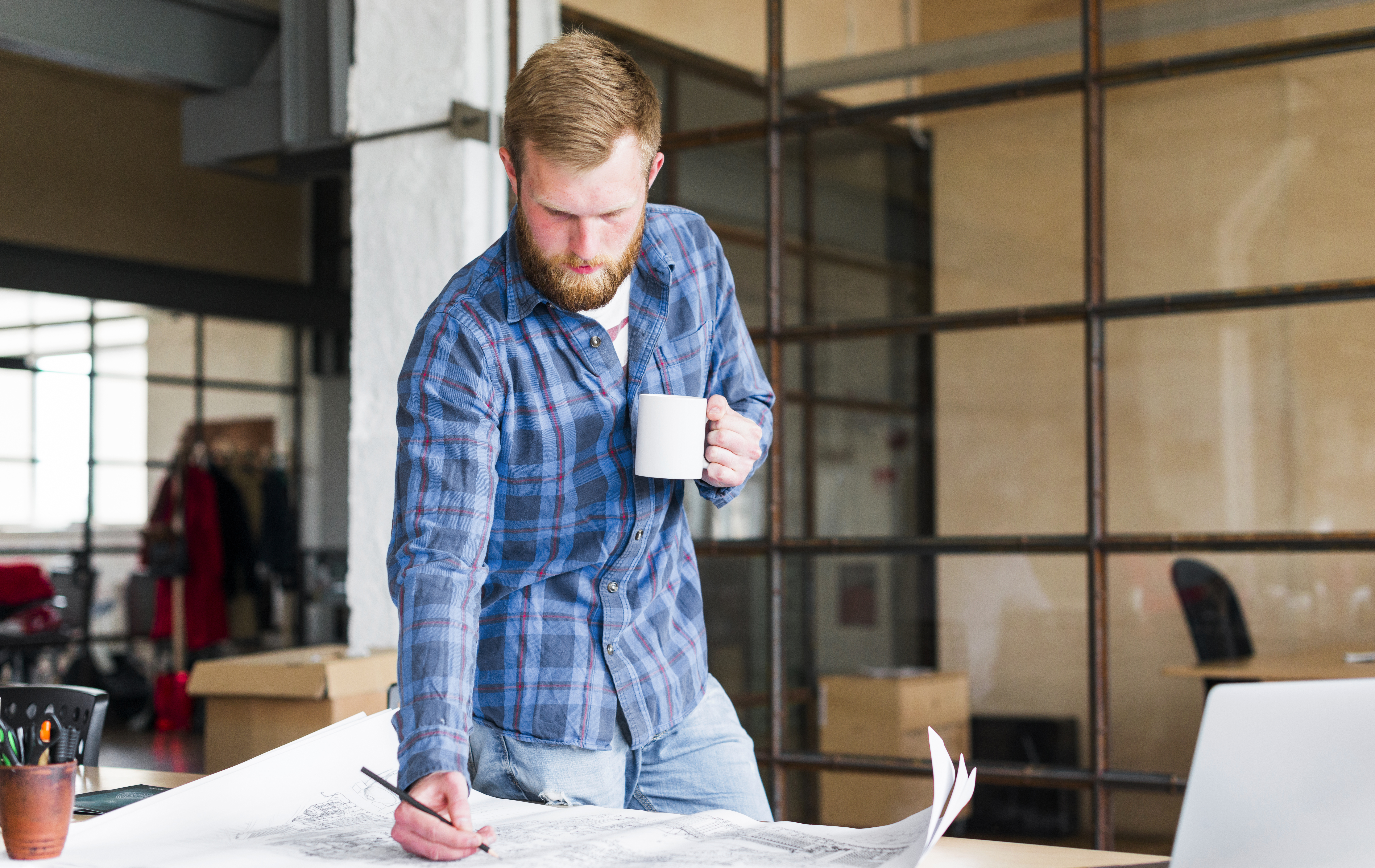 man-drawing-blue-print-with-holding-coffee-cup-his-office.jpg