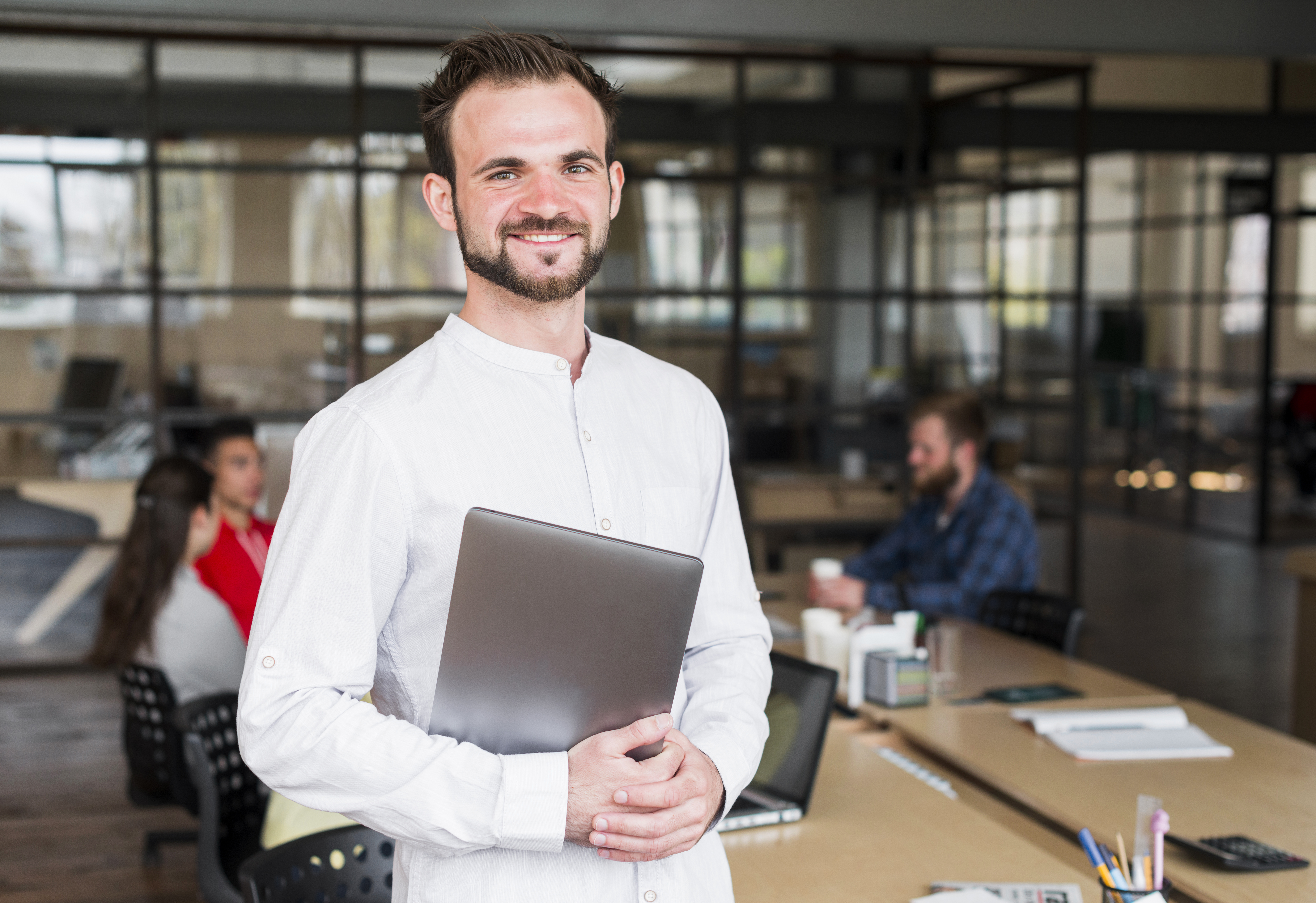 happy-young-businessman-looking-camera-holding-laptop-office.jpg