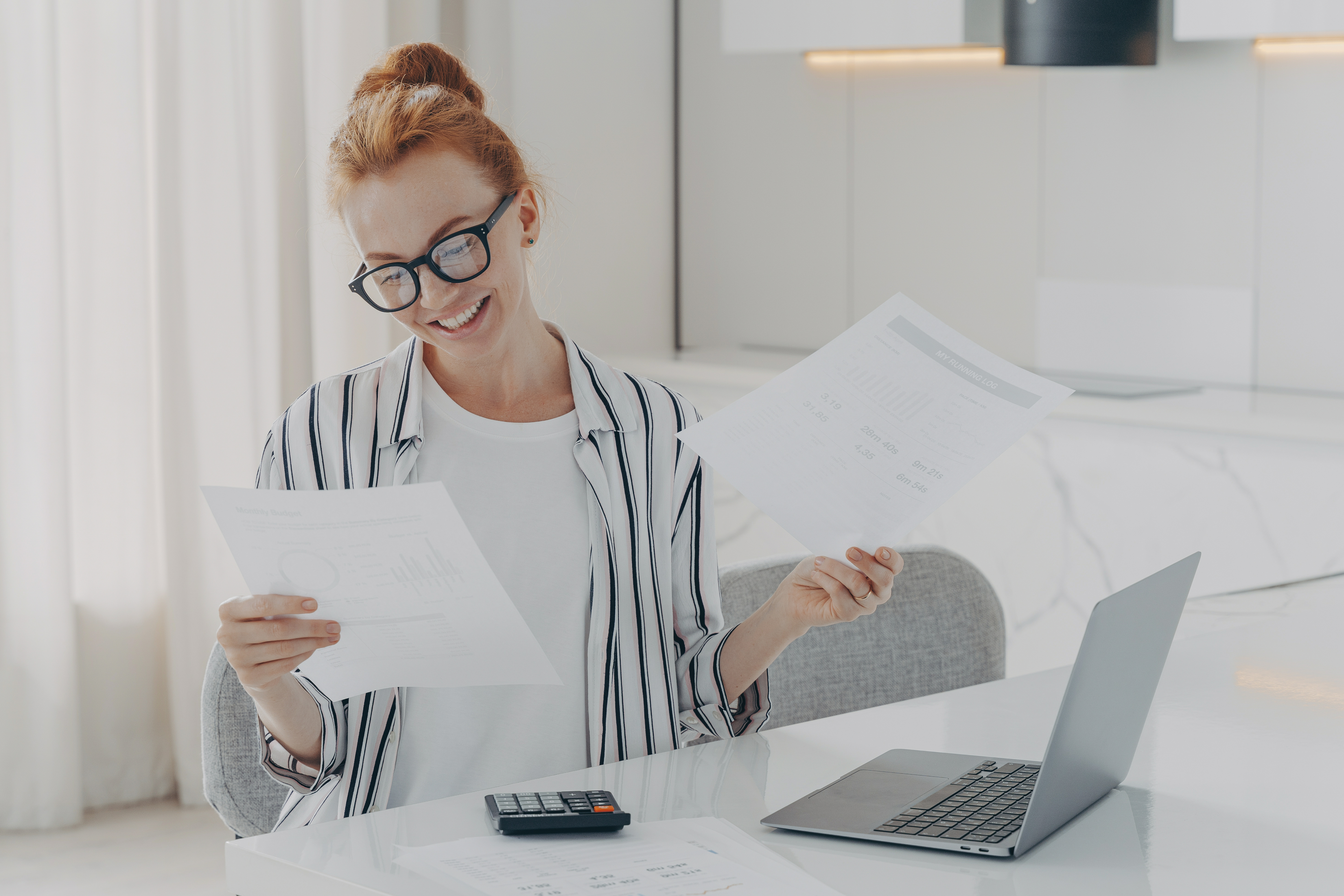 young-excited-redhead-woman-sitting-table-home-feeling-happy-after-checking-domestic-bills.jpg