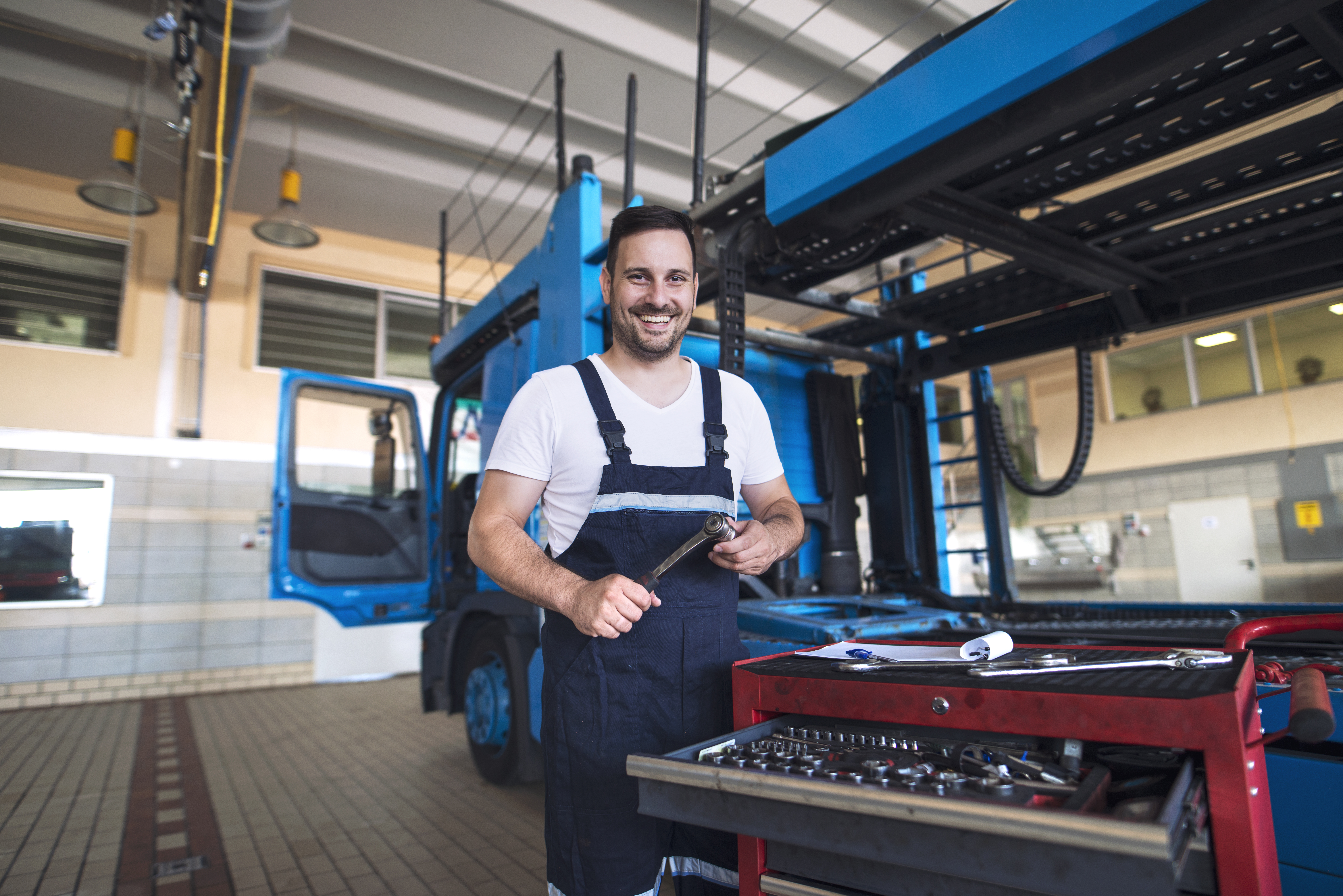 portrait-positive-smiling-truck-serviceman-with-tools-standing-by-truck-vehicle-workshop.jpg