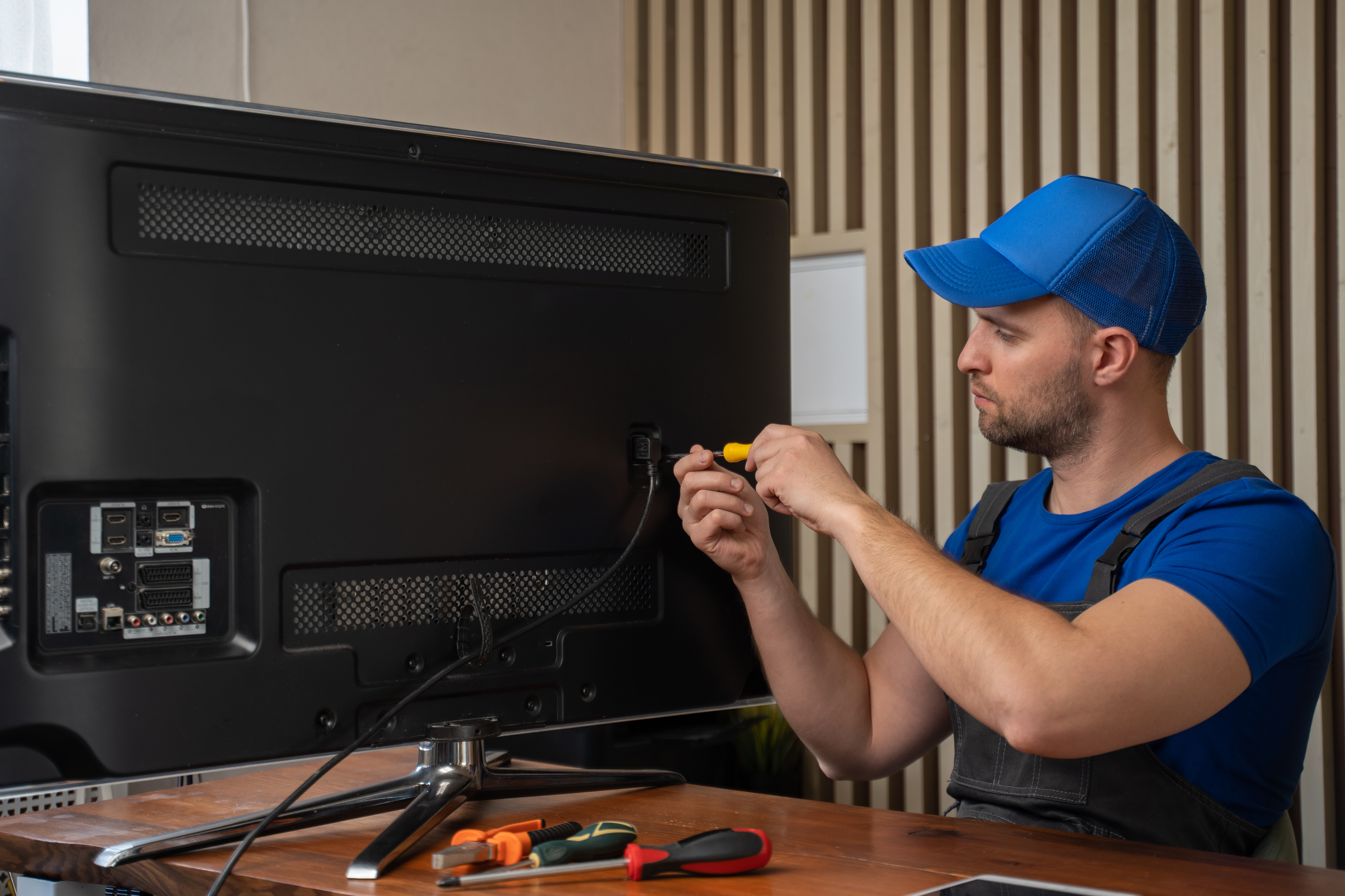 master-blue-tshirt-smiles-after-repairing-tv-set-connector-with-screwdriver-sitting-table.jpg