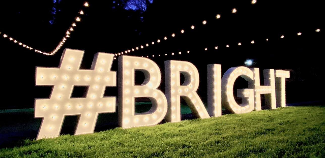 XXL-Leuchtbuchstaben mit dem Schriftzug #BRIGHT bei Nacht auf einer Wiese