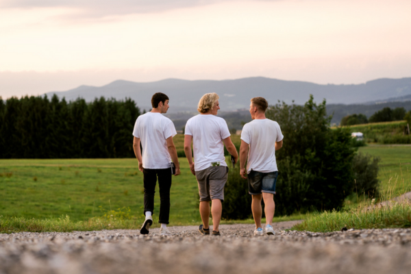 Drei Fundraiser von hinten, wie sie über ein Feld laufen in den Sonnenuntergang