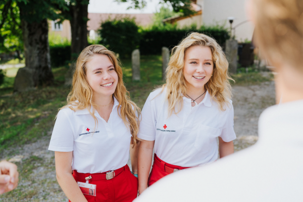 2 lächelnde Fundraiserinnen, die in der Roten Kreuz Uniform gleich fundraisen gehen