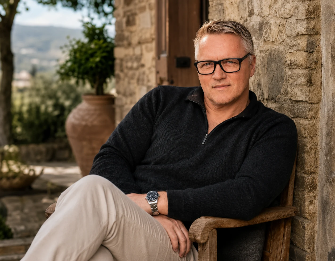 Philipp Lindner, marketing online per coach e consulenti, seduto su una panca di legno davanti a un muro di pietra in Toscana