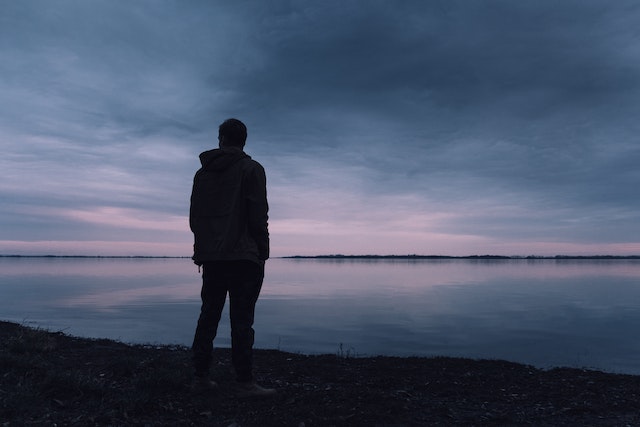 Mann steht alleine vor einem See