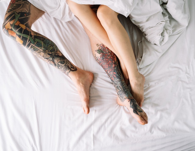 Beine von Mann und Frau im Bett