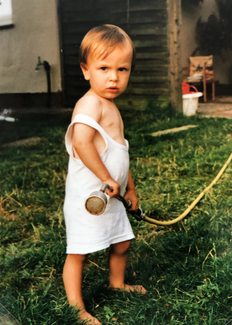 Hendrik Fuchs als Kind mit einer Gartenspritze im Grünen.