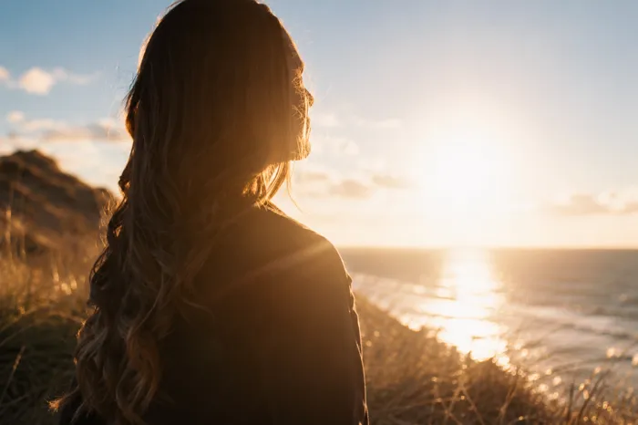 Frau blickt bei Sonnenuntergang aufs Meer