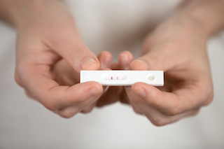 Haende zeigt einen Schwangerschaftstest