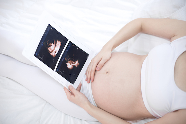 Schwangere Frau schaut Ultraschall Bilder an