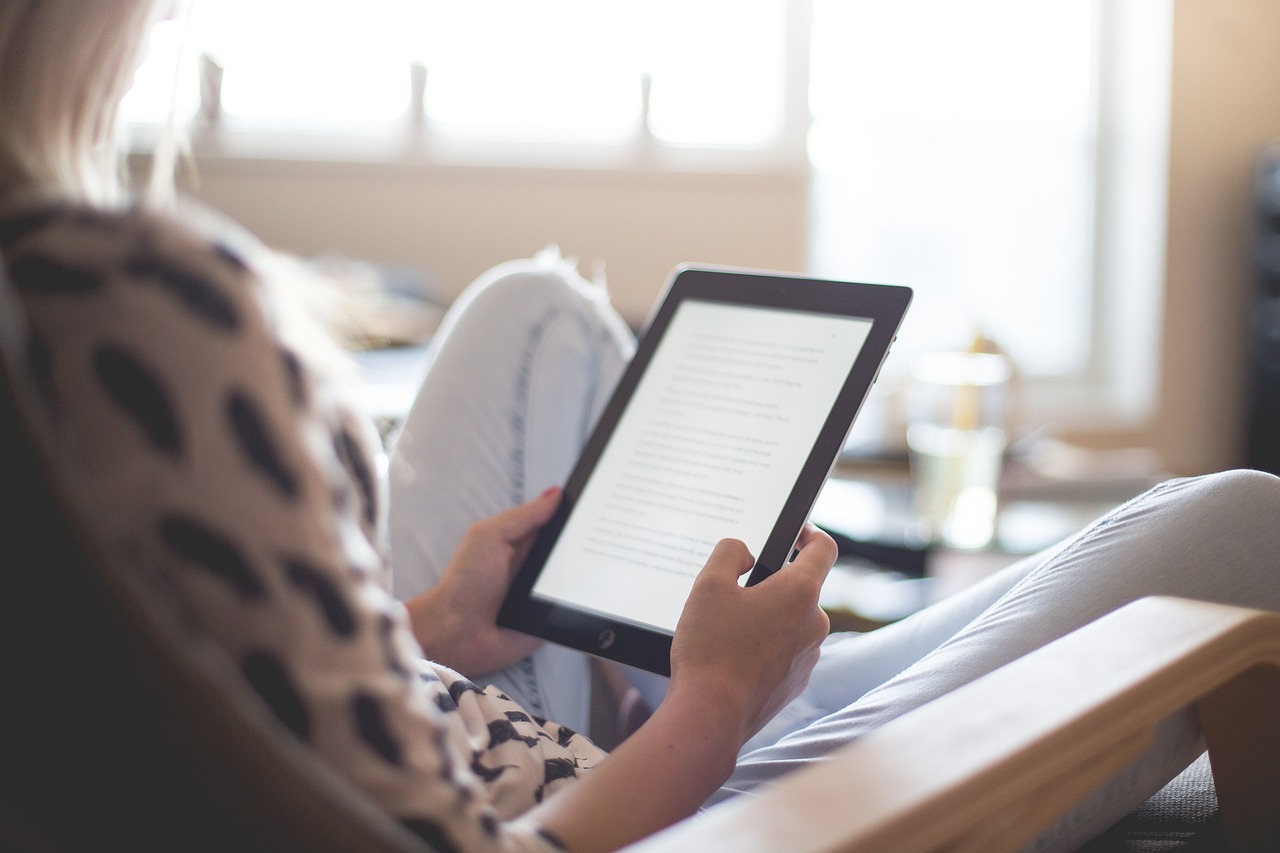 Frau sitzt auf einem Stuhl und liest ein Ebook