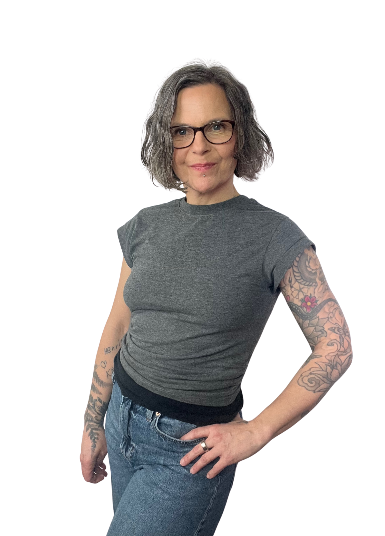 Bild von Inga Wiegert, im grauen T-Shirt und Jeans, mit Brille und einer Hand in die Hüfte gestützt.