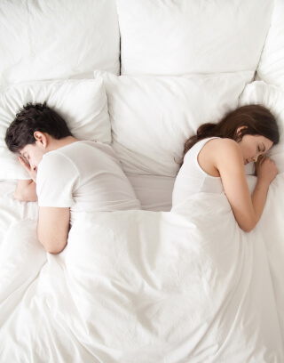 Frau und mann in einer Liebesbeziehung haben Beziehungskonflikte und liegen Rücken an Rücken im Bett