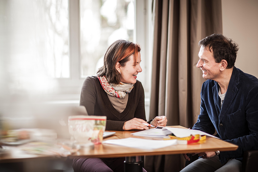 Foto von Franiska Gostner und einem Mann sitzen am Tisch und besprechen Themen im Coaching