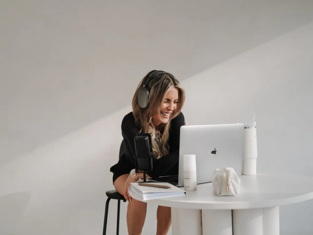 Nina lacht und arbeitet an ihrem Laptop.