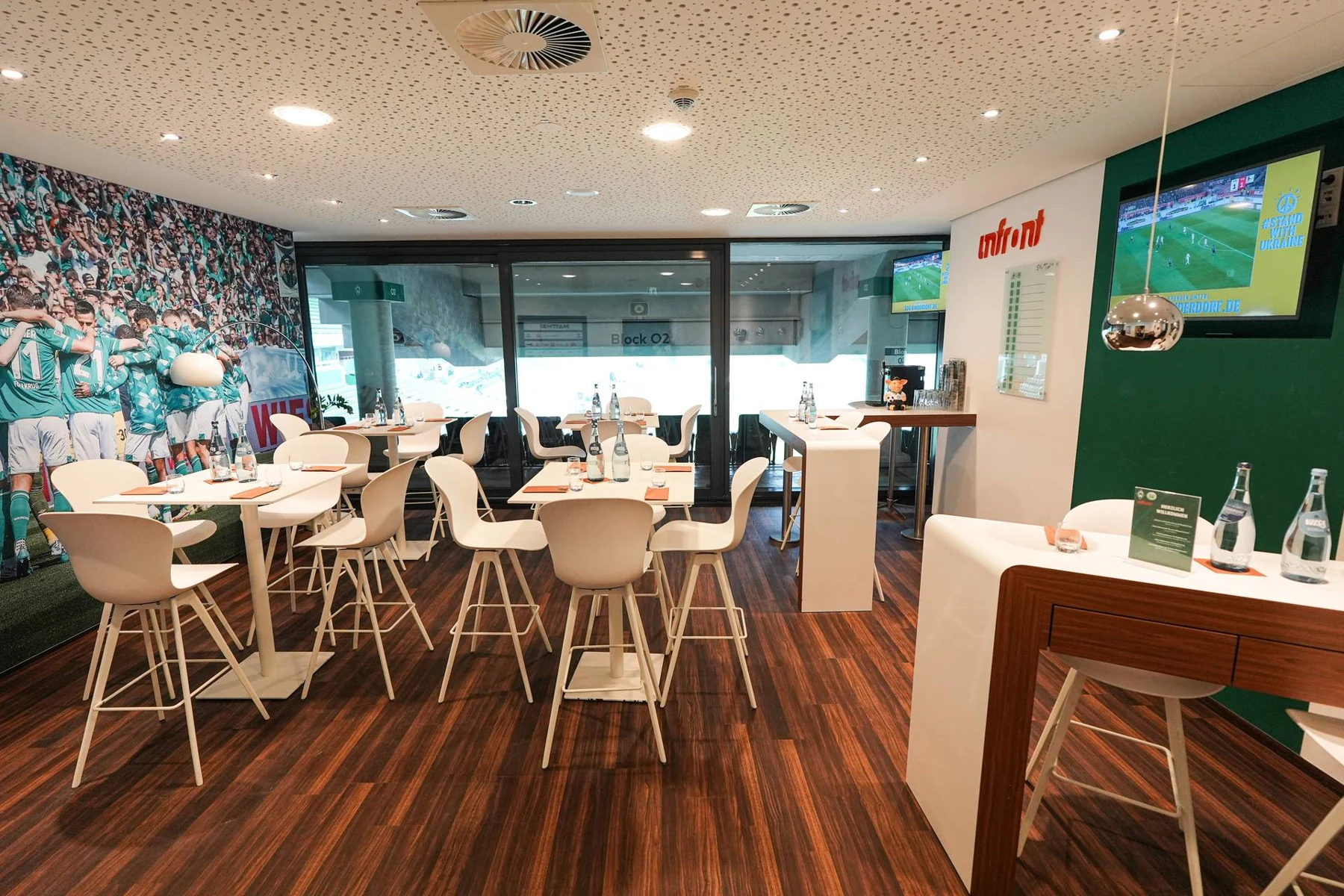 Eine Loge im Weserstadion mit hellen Tischen, Sitzgruppen und Blick Richtung Tribüne
