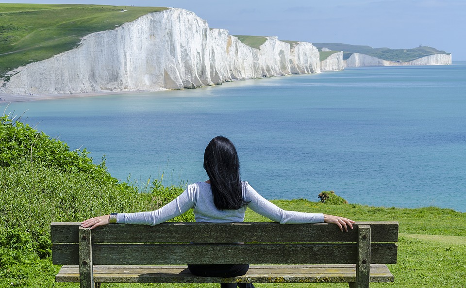 Diese Frau sitzt auf einer Bank mit Blick auf das schöne Meer und baut dabei ihren Stress ab