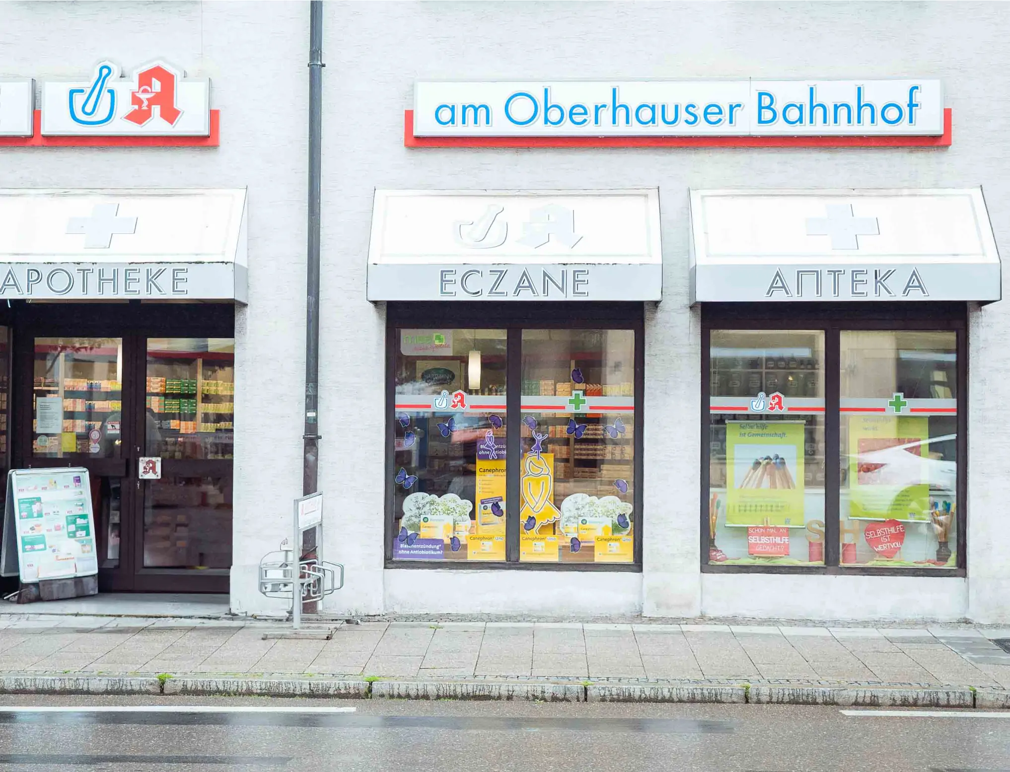 Außenansicht der Apotheke am Oberhauser Bahnhof in Augsburg, zentral gelegen mit leicht zugänglichem Eingang und Apothekenschild.