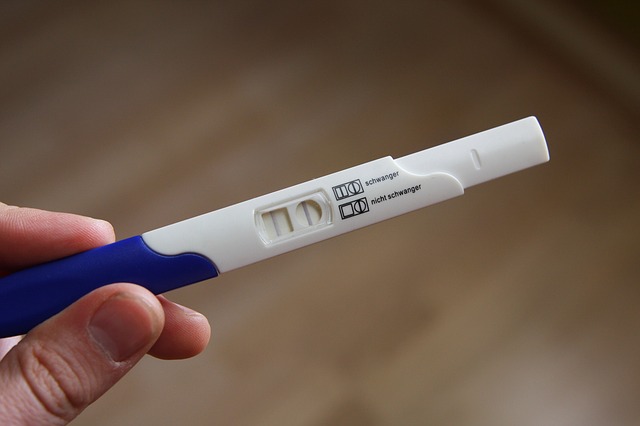Frau hält einen positiven Schwangerschaftstest in der Hand