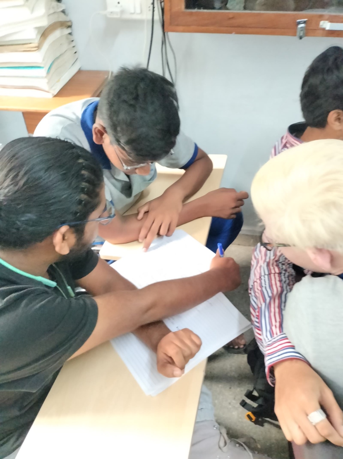 A UUF volunteer guiding a visually impaired student during a writing activity