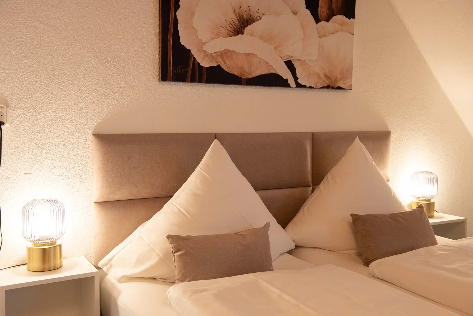 Doppelbett mit hellem Kopfteil und gerahmtem Wandbild