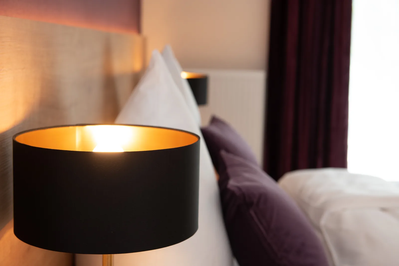 Nachttischlampe mit schwarzem Schirm neben dem Doppelbett