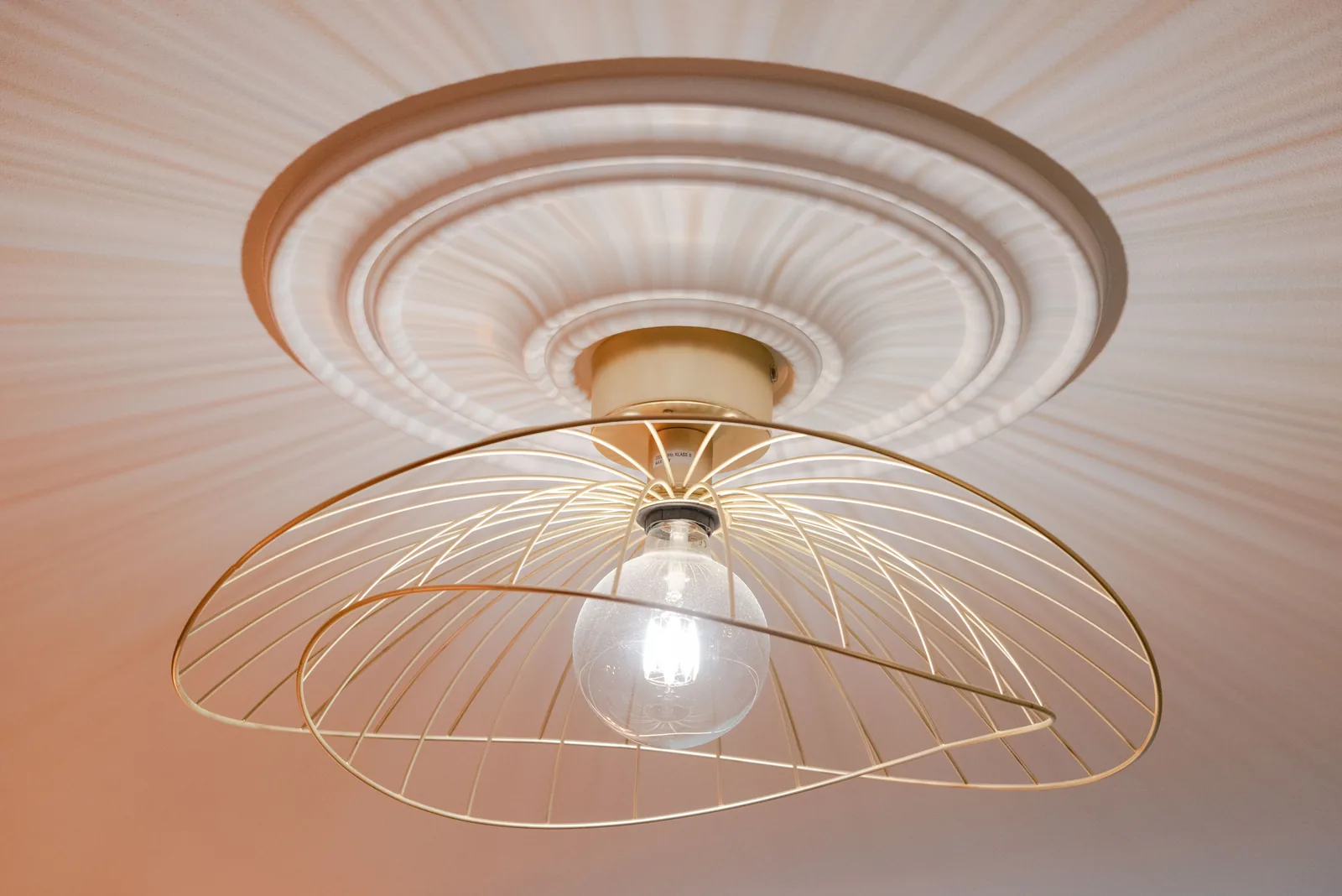 Deckenleuchte mit goldfarbenem Schirm und Stuckrosette