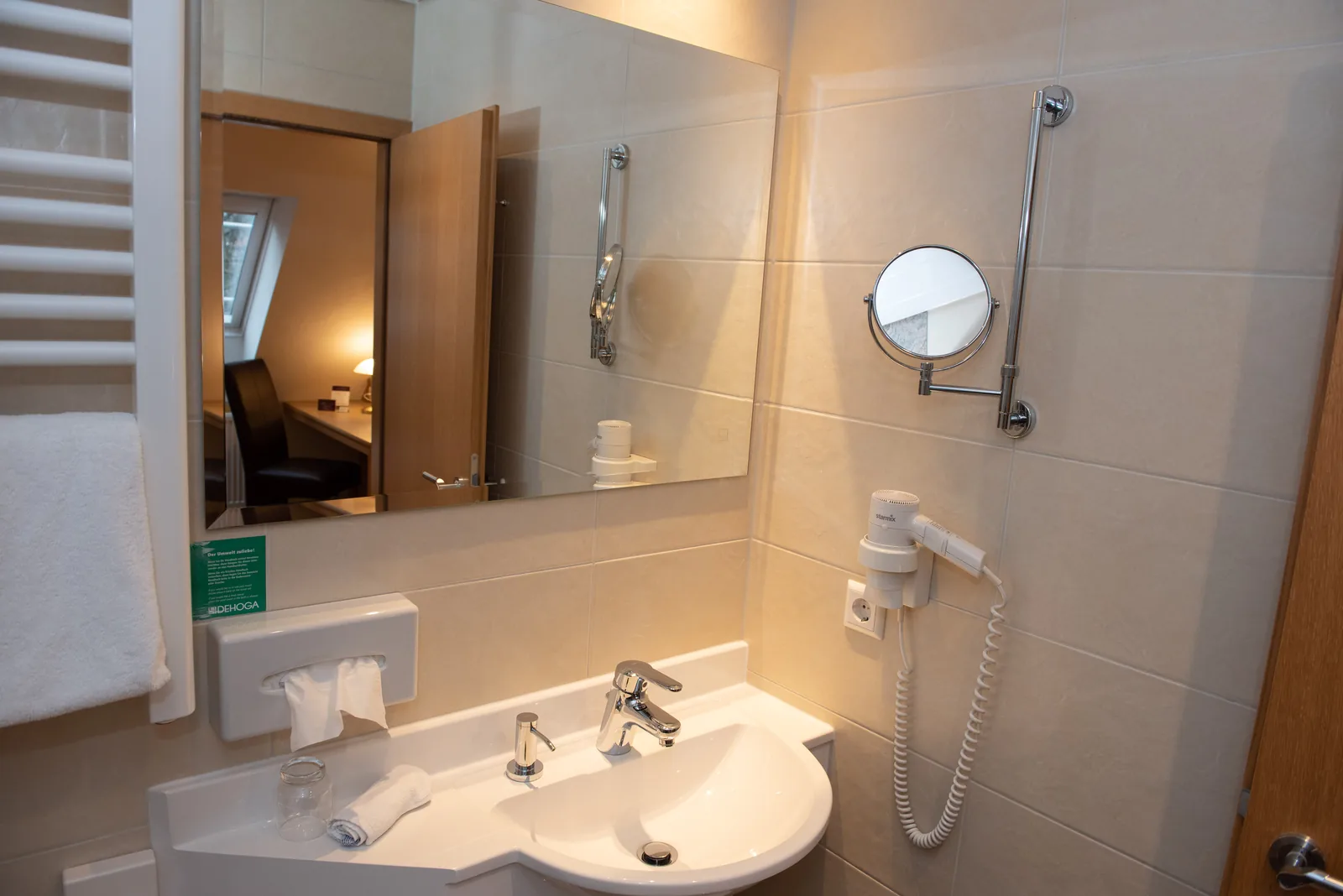 Badezimmer mit Waschbecken, Spiegel und Handtuchheizkörpe