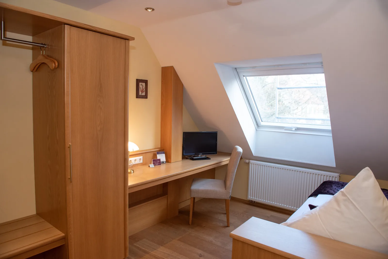 Einzelzimmer mit Holzmöbeln und Dachfenster