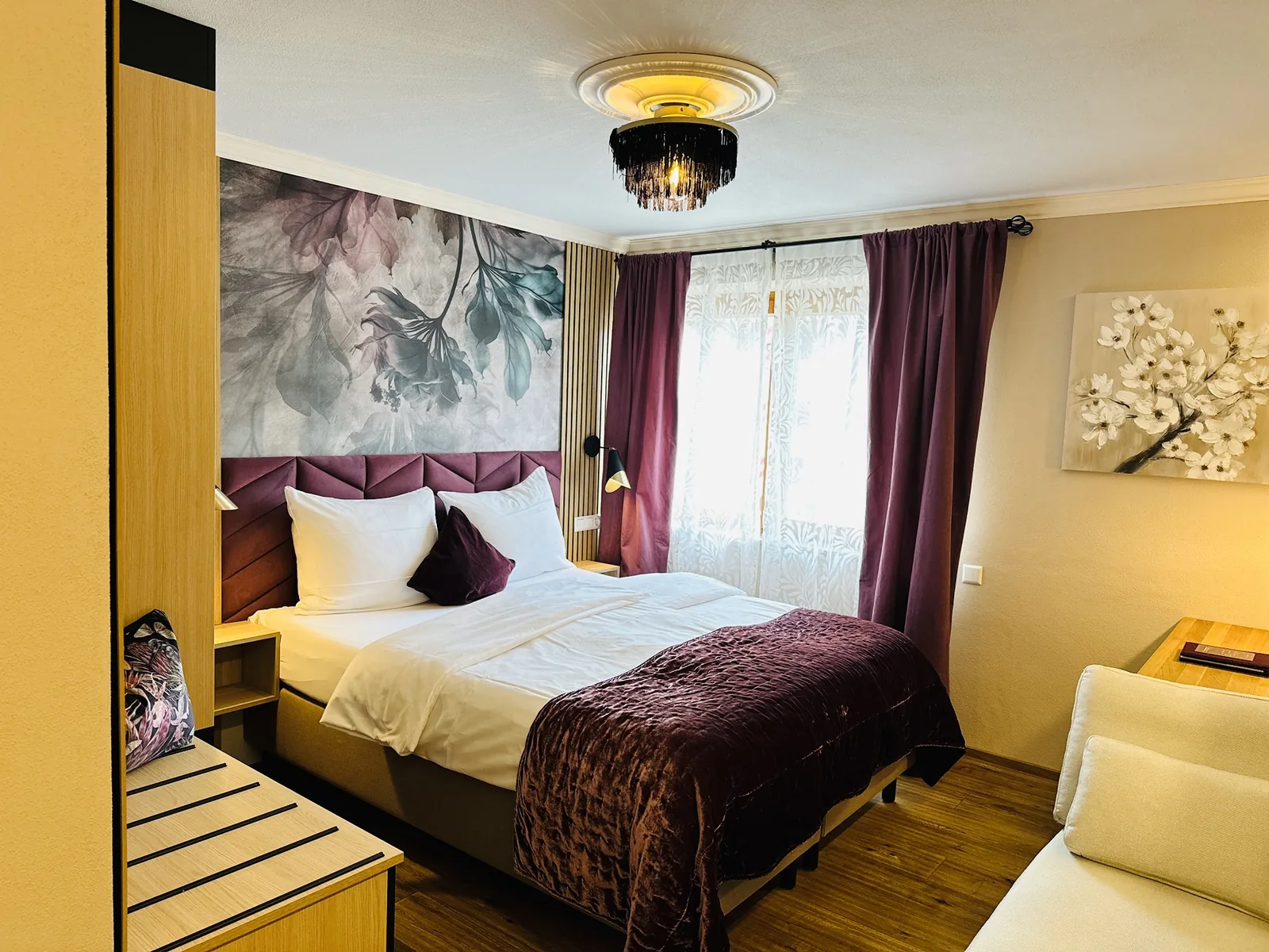 Komfort Doppelzimmer mit Bett, gelbem Sessel und Floraltapete