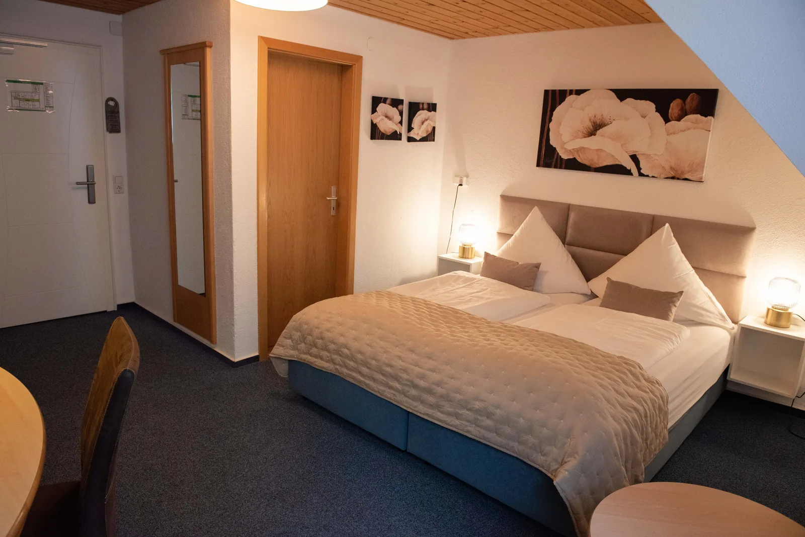 Gasthofzimmer mit hellem Doppelbett und Zugang zum Bad