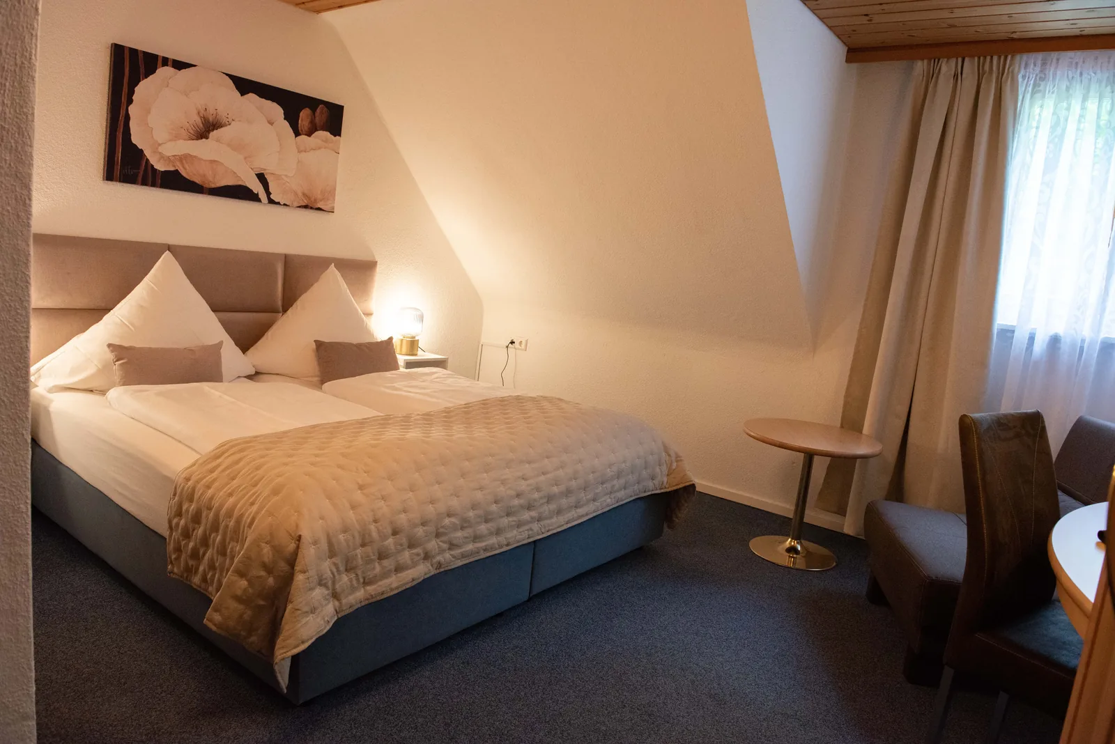 Gasthofzimmer mit Doppelbett, Tisch und Stühlen am Fenster
