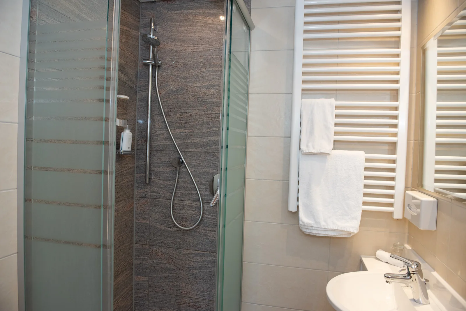 Badezimmer mit Glasdusche und Handtuchheizkörper