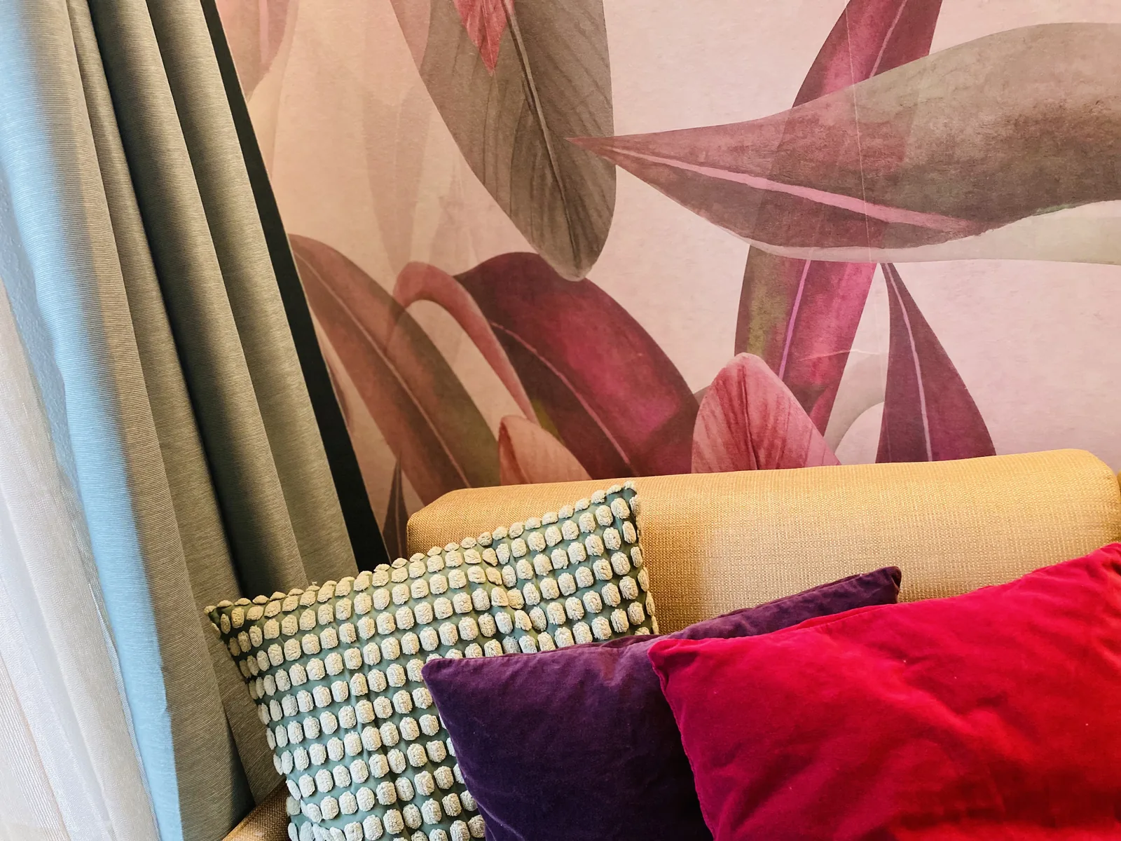 Ecksofa mit farbigen Kissen vor Floraltapete in der Junior Suite