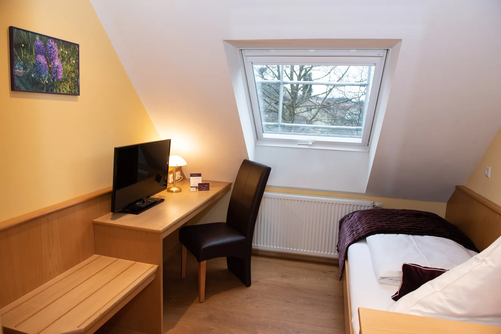 Einzelzimmer mit Schreibtisch und Dachfenster