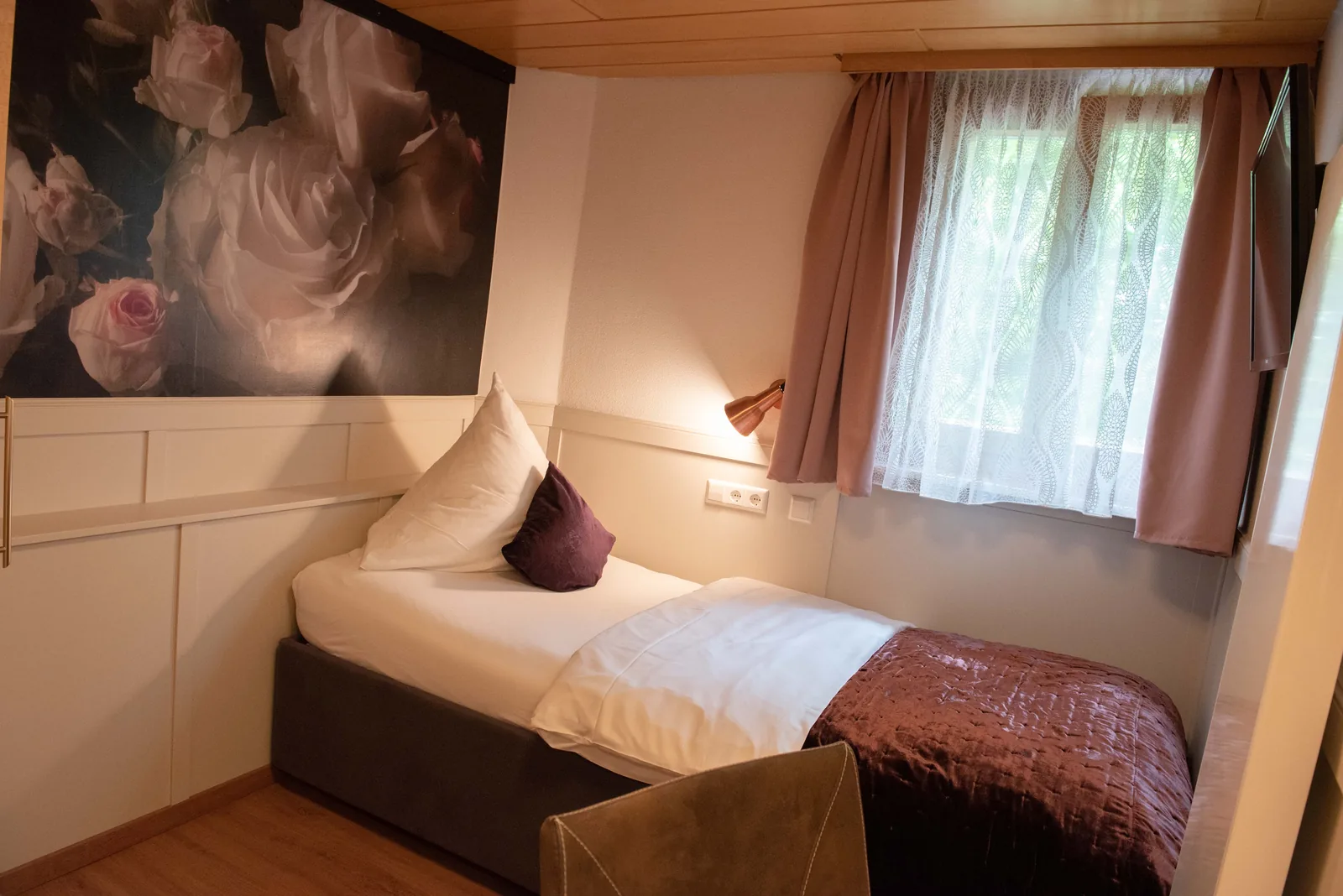 Einzelzimmer mit Bett, Floraltapete und Fenster