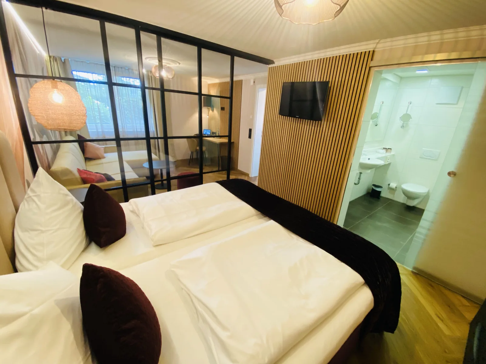 Doppelbett vor der Glasschiebewand in der Junior Suite