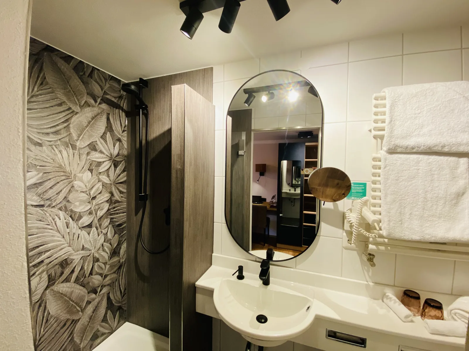 Badezimmer mit rundem Spiegel und floraler Wandgestaltung