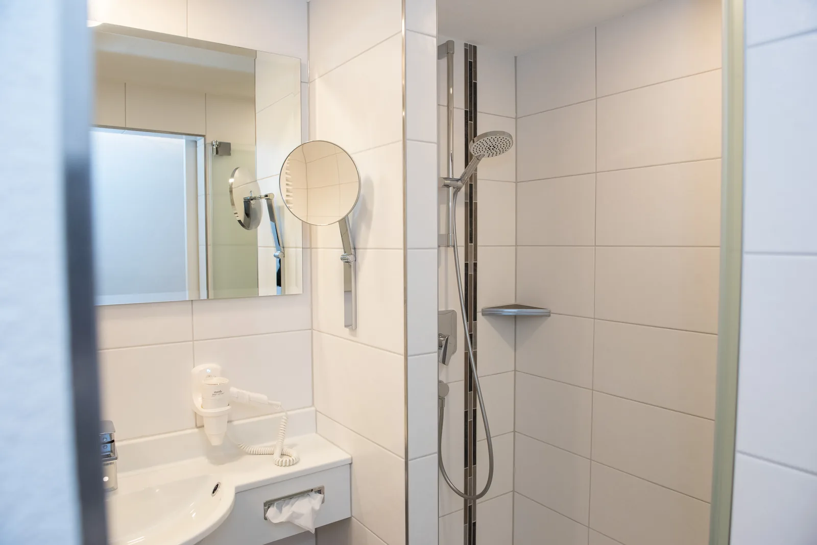 Badezimmer mit Waschbecken, Spiegel und bodennahem Duscheinstieg