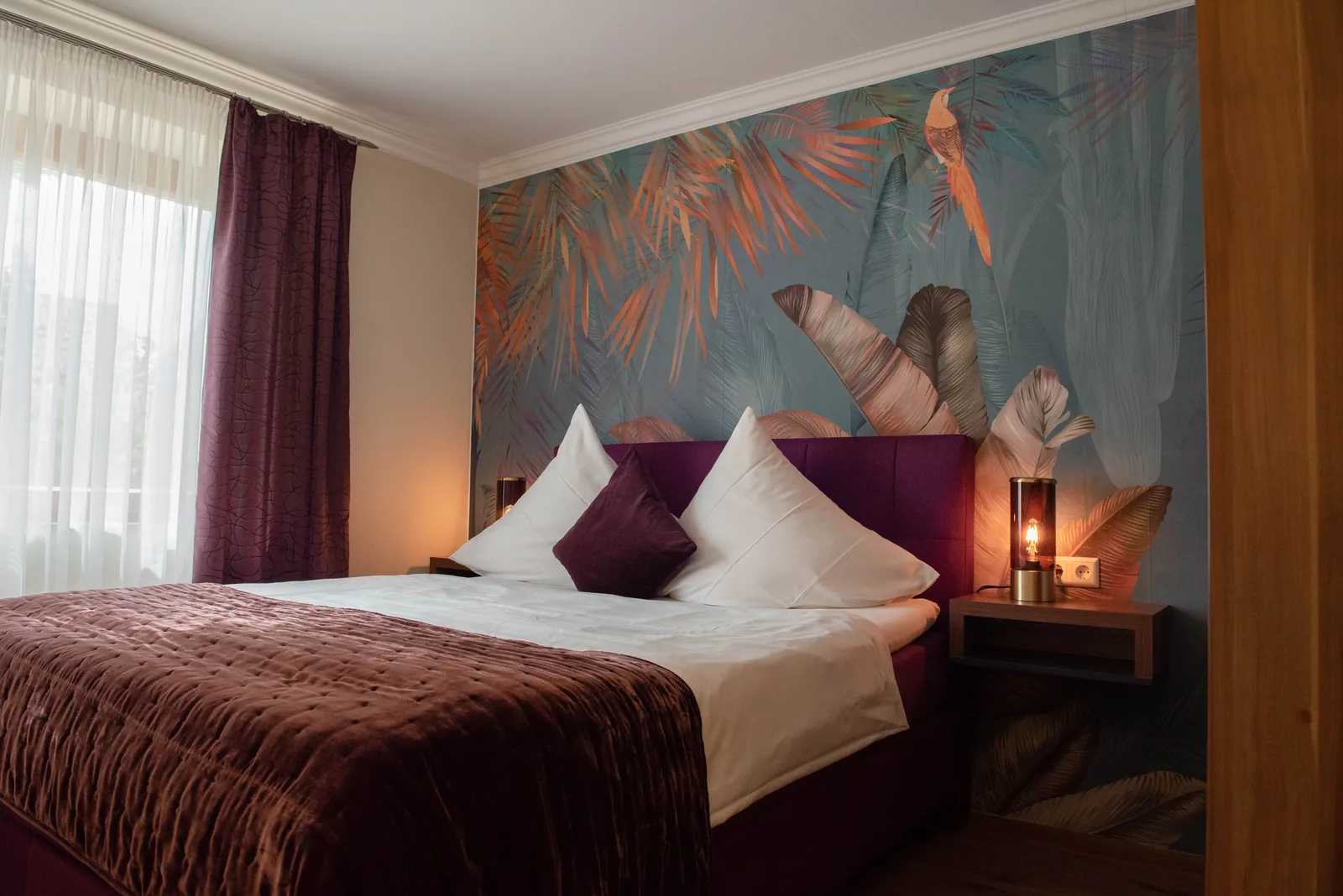 Komfort Doppelzimmer mit Floraltapete und violetten Kissen