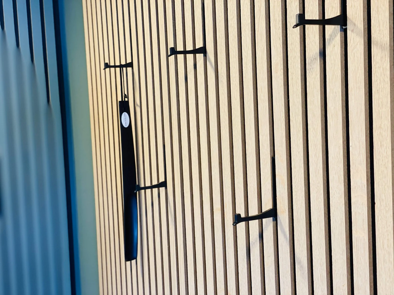 Garderobenhaken vor einer Wand mit Holzlamellen