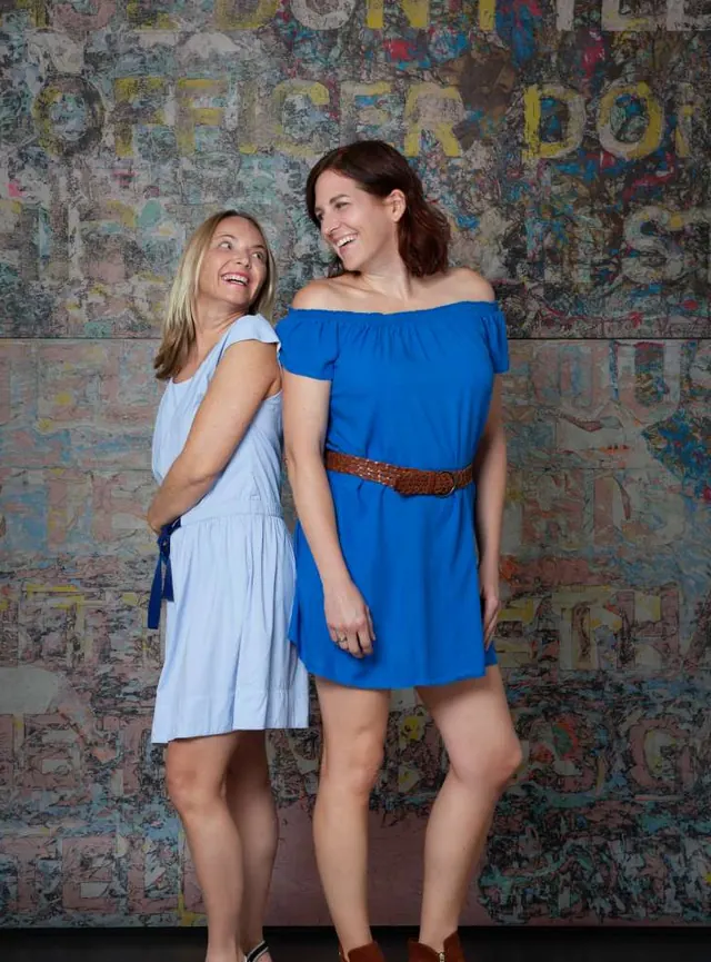 Katja und Verena lachend vor einer bunten Wand